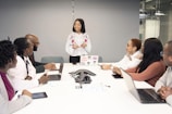 a group of people sitting around a table with laptops