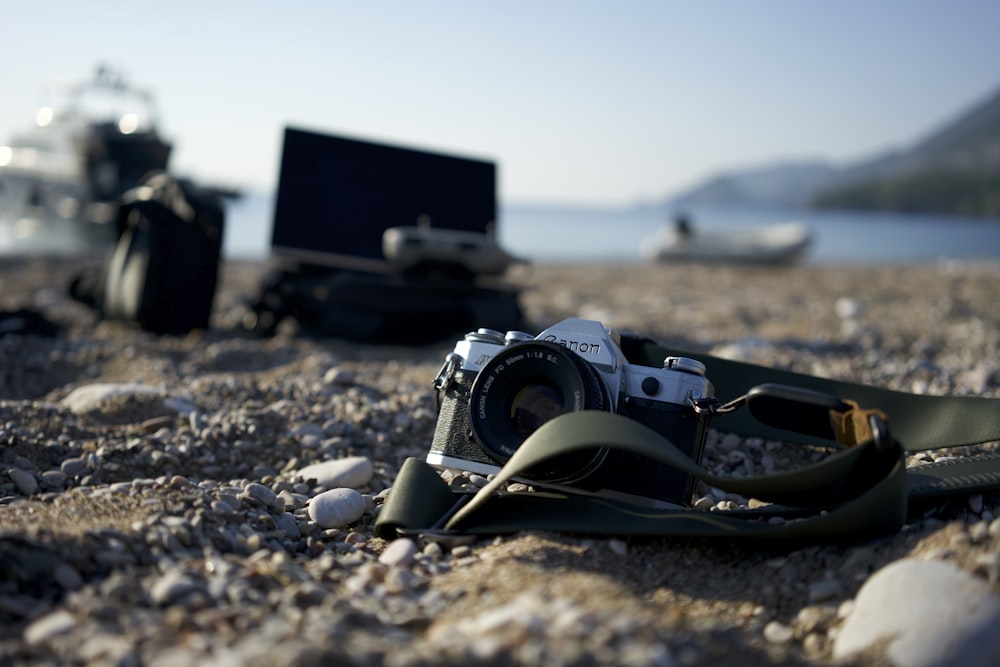 uma câmera sentada em uma praia ao lado de um laptop