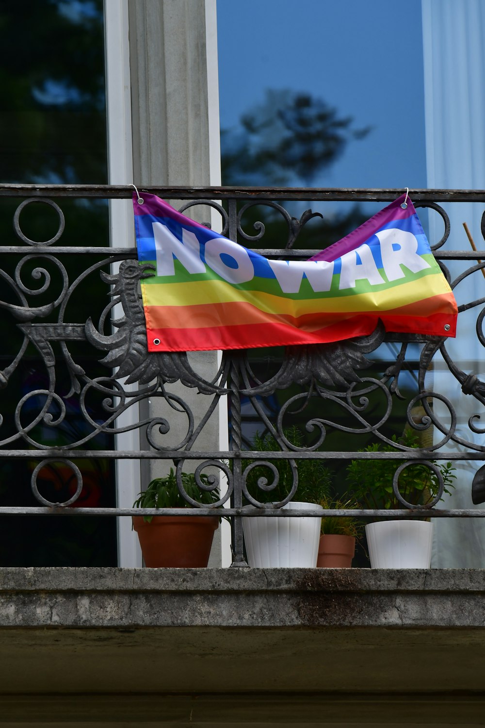 a rainbow flag on a balcony with potted plants