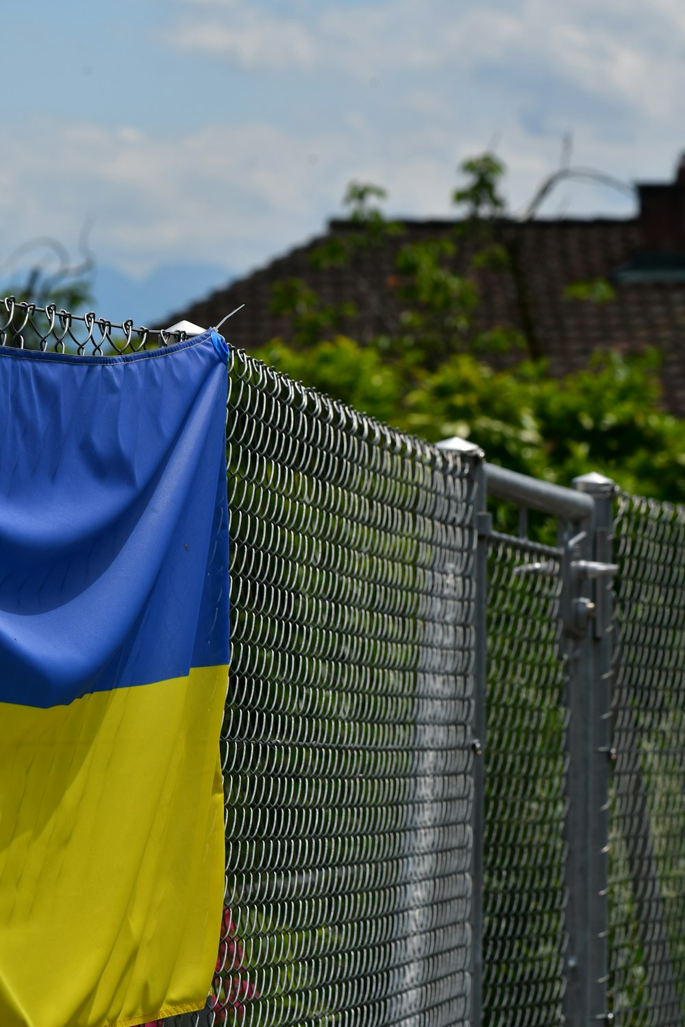 a blue and yellow flag hanging on a chain link fence