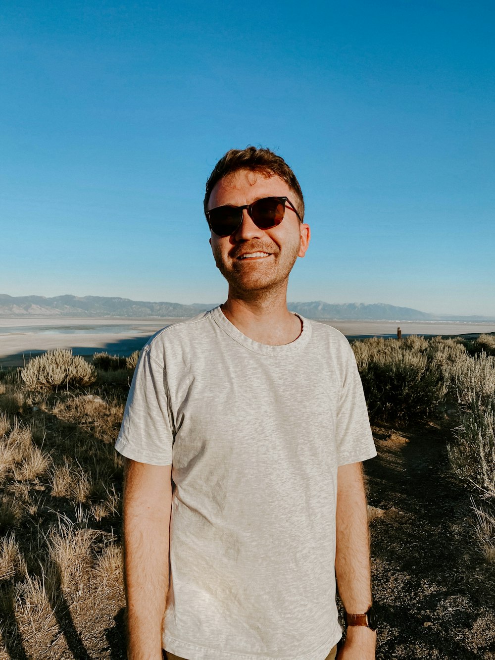 a man wearing sunglasses standing in a field