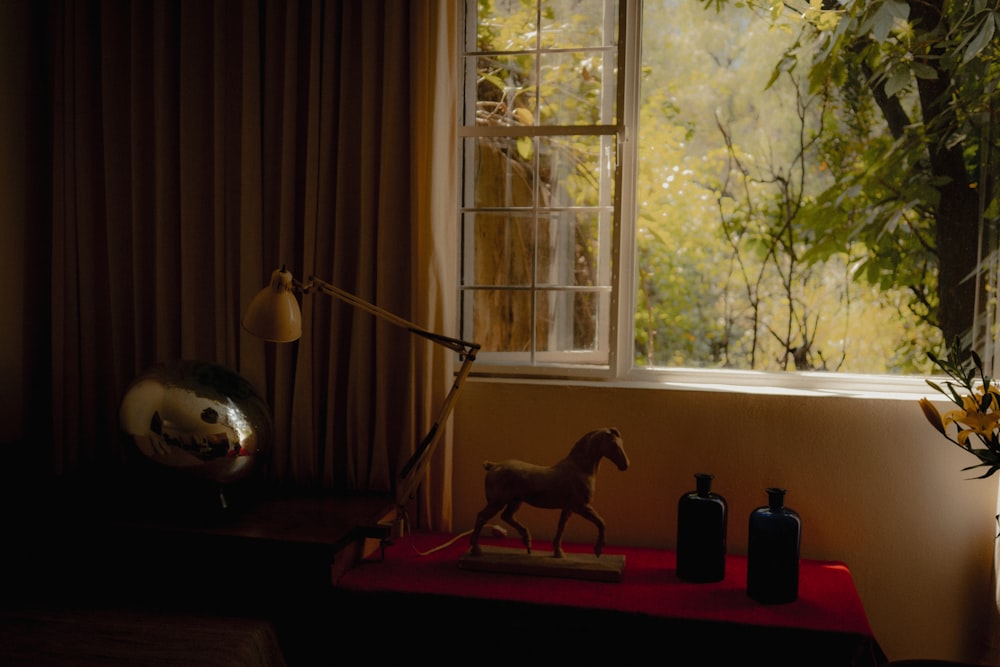 a horse figurine on a table next to a window