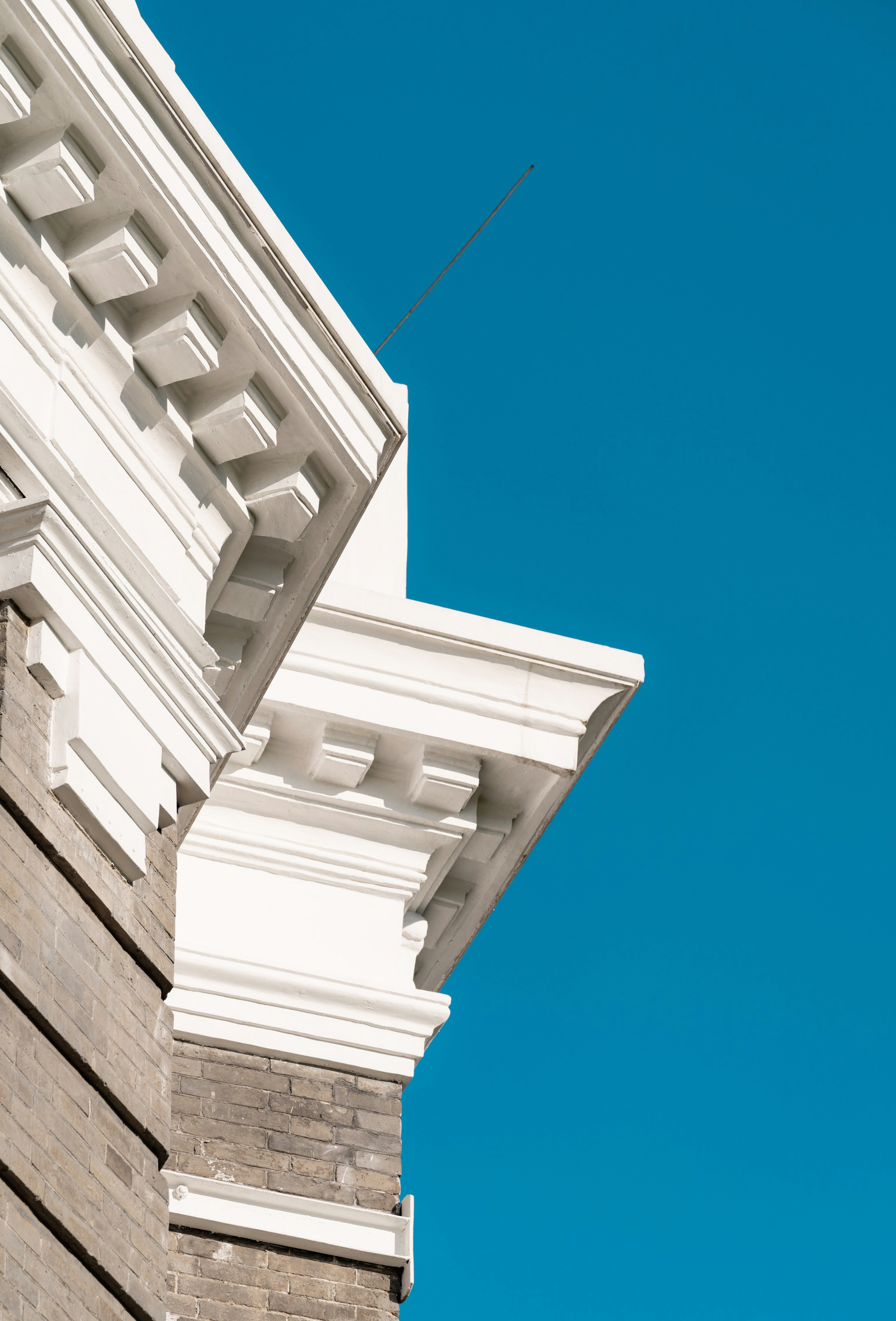 A white building facade photographed against a clear blue sky.