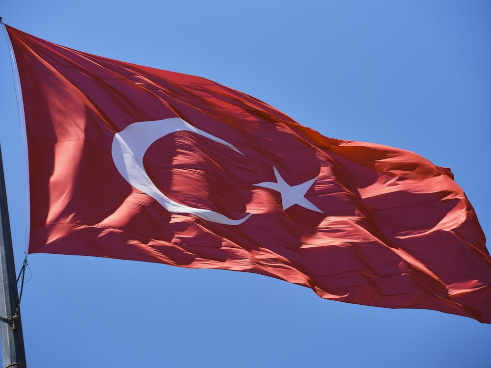 a flag flying in the wind with a blue sky in the background