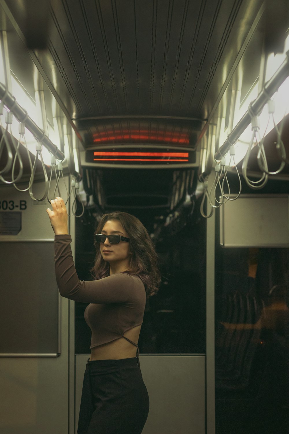 a woman standing on a train holding onto the lights