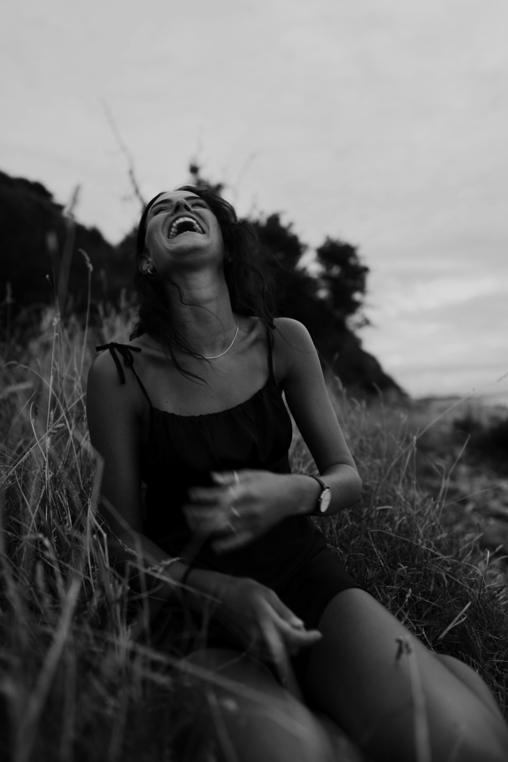 una donna seduta in un campo che ride