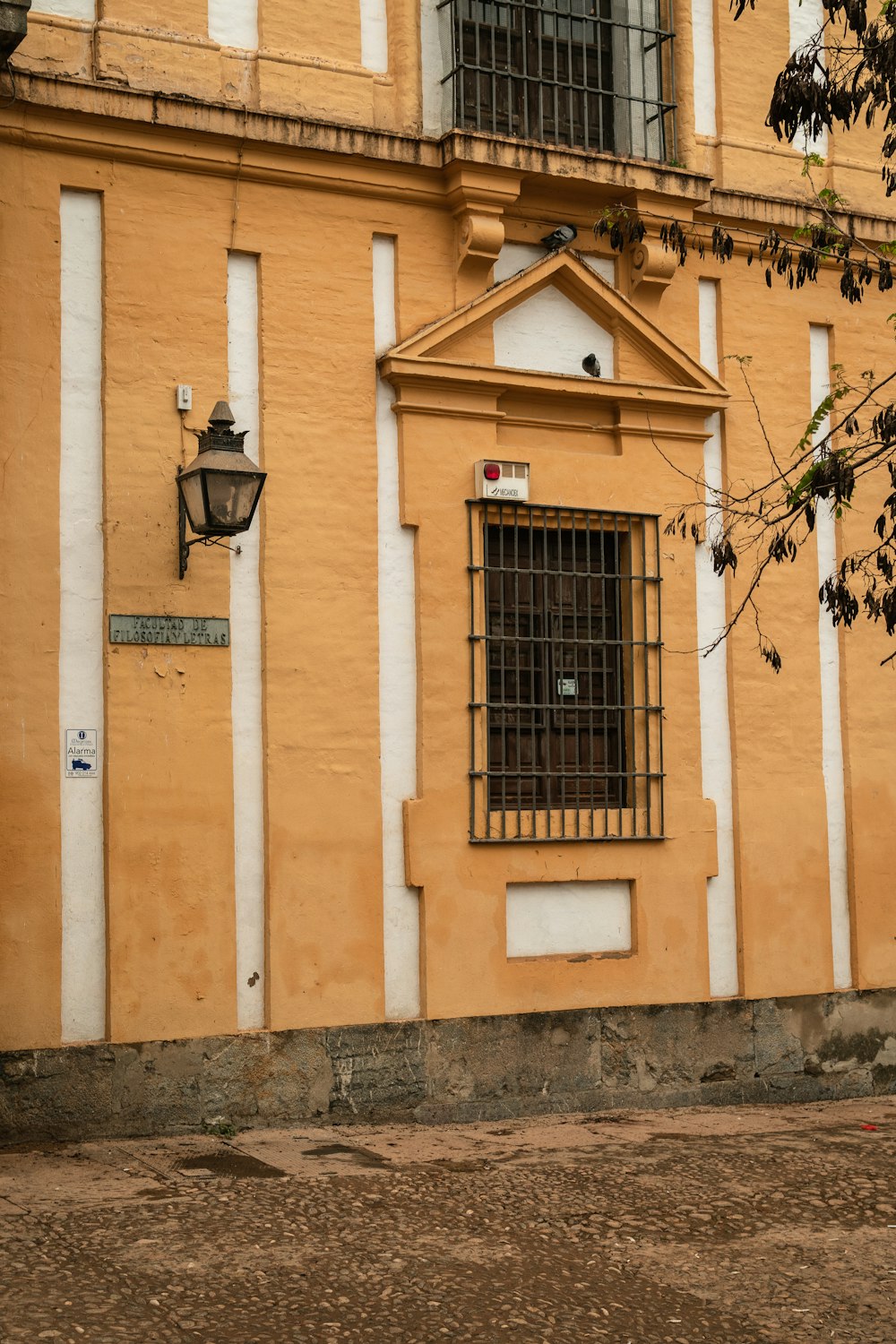 a yellow building with a window and bars on it