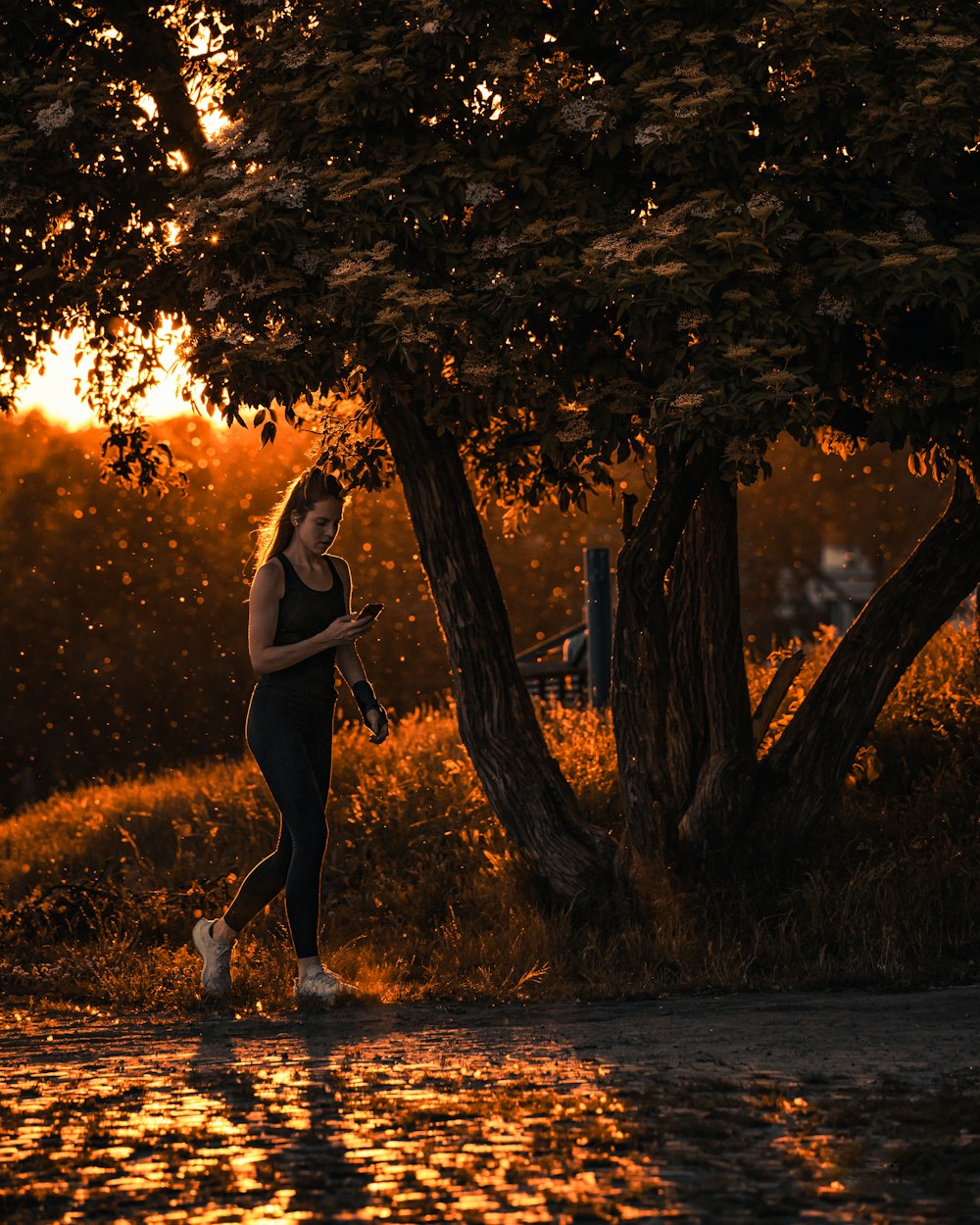 a woman walking down a street next to a tree