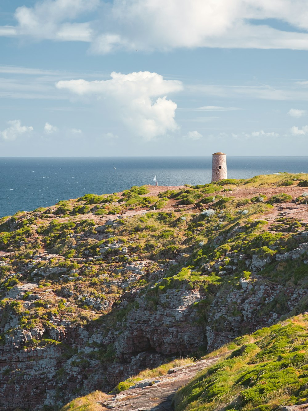 Ein Leuchtturm auf einem Hügel mit Blick auf den Ozean