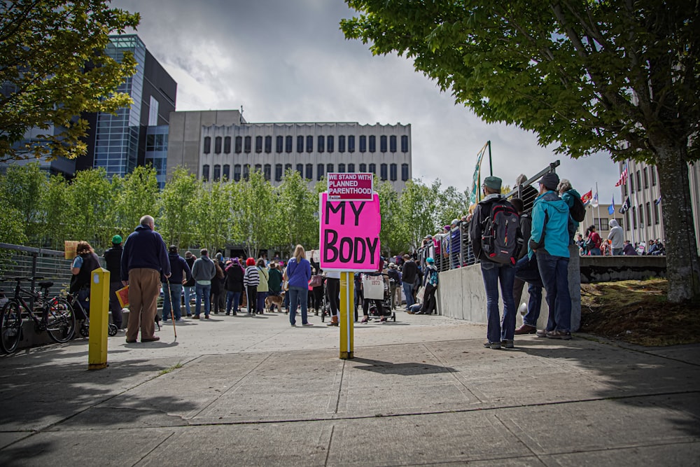 a group of people standing around a pink sign