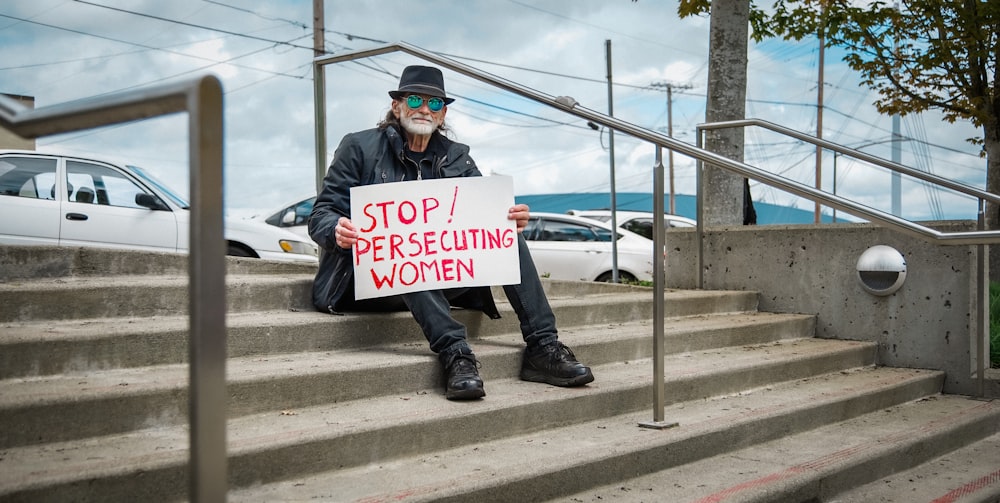 a man sitting on steps holding a sign