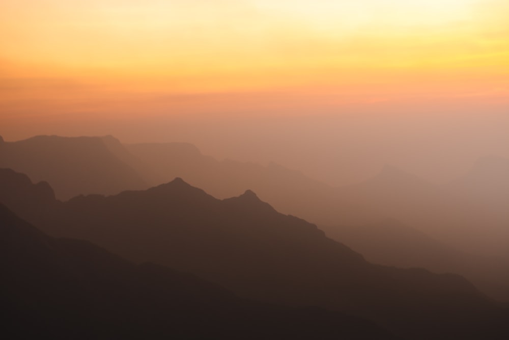 the sun is setting over a mountain range