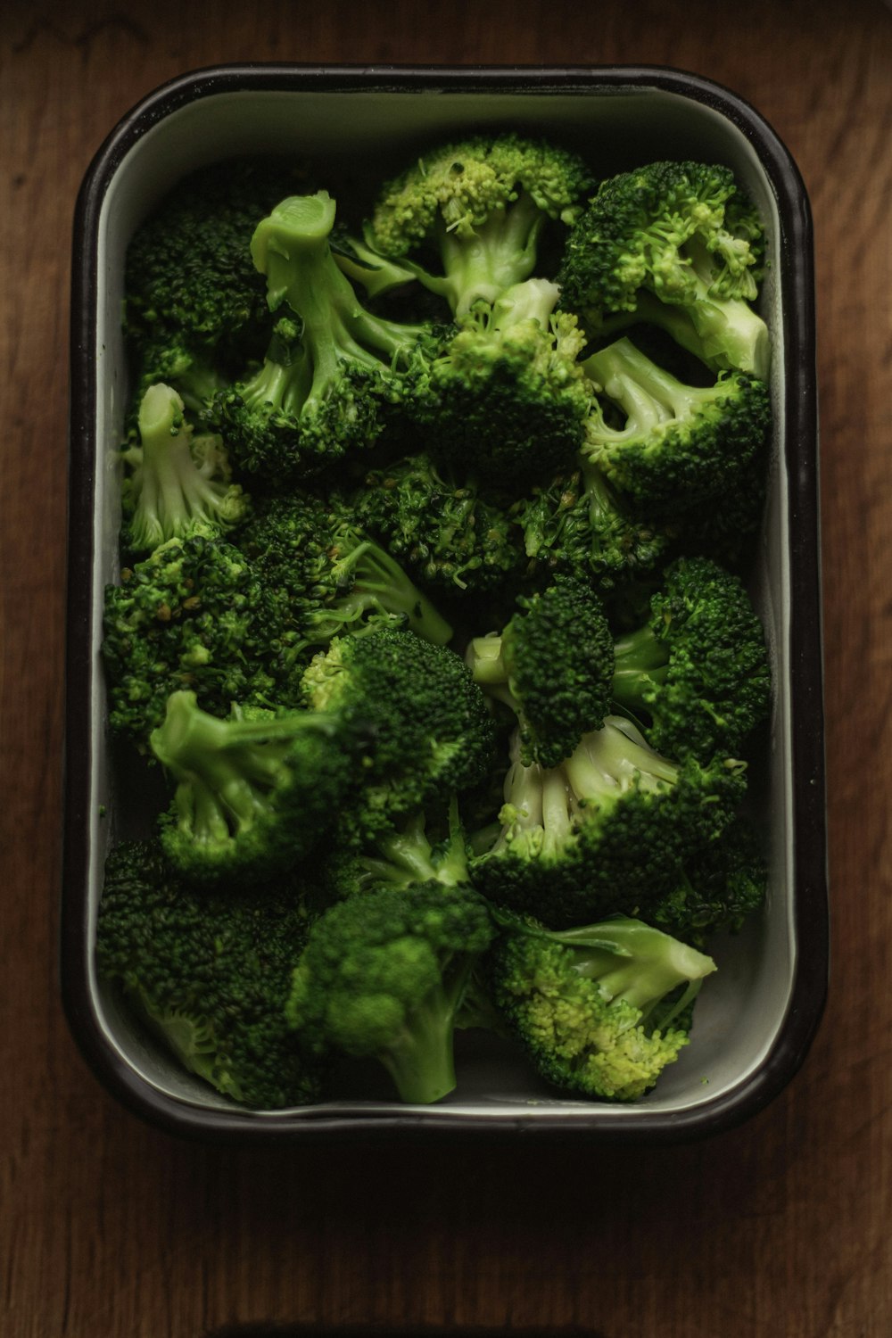 a dish of broccoli on a wooden table