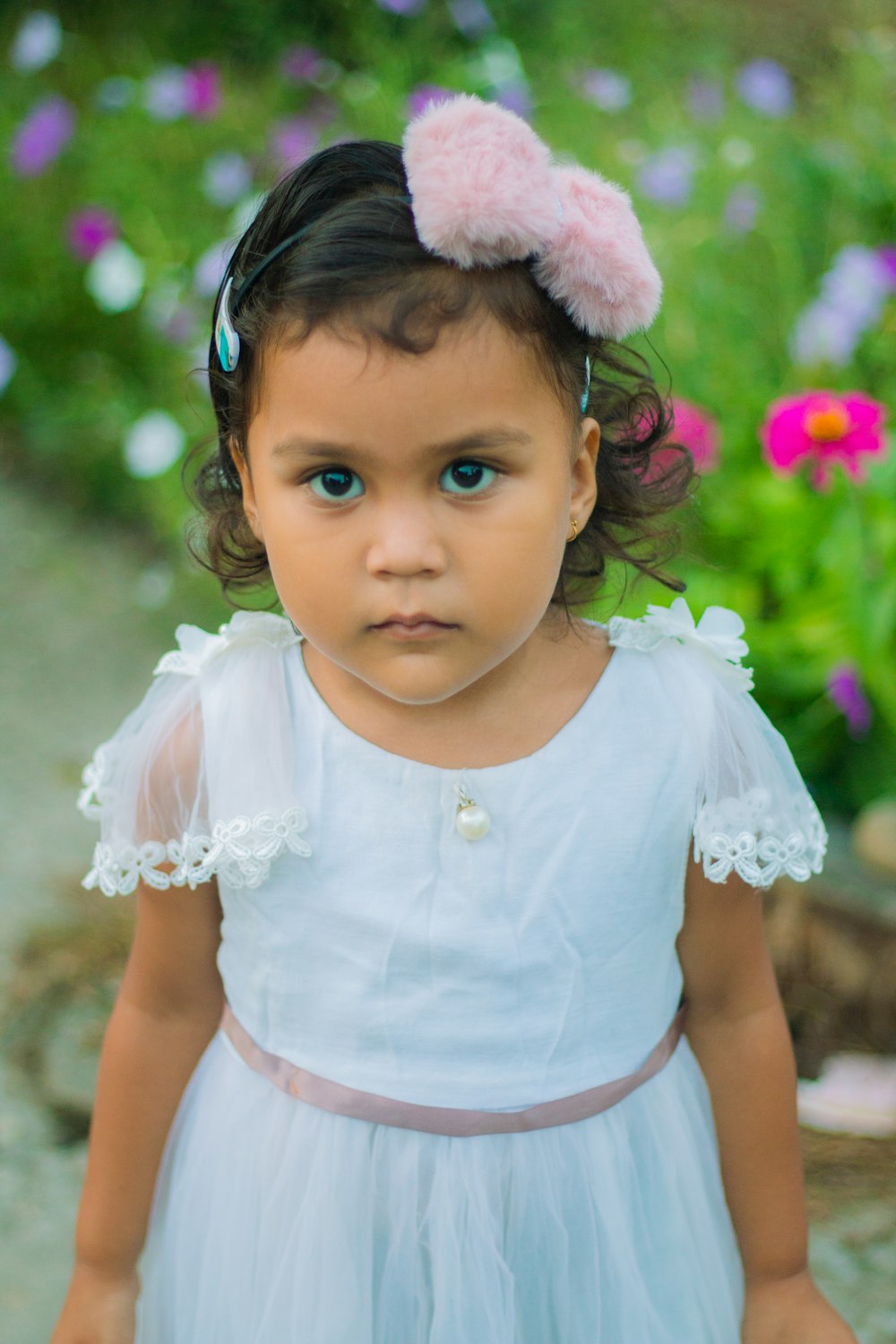 a little girl wearing a white dress and a pink headband