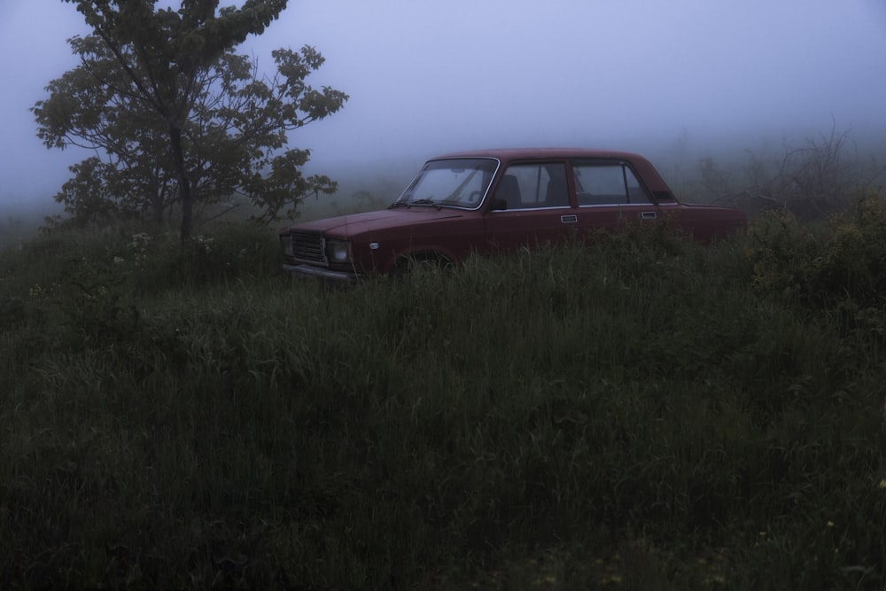 an old car is sitting in a field on a foggy day