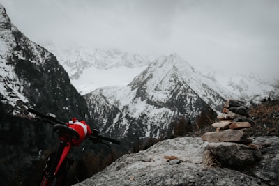 Ridesleeve in slate color resting on rugged outdoor rocks with snow-capped peaks behind.
