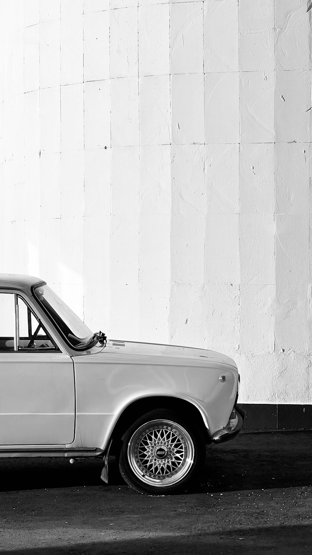 a black and white photo of a car parked in front of a building