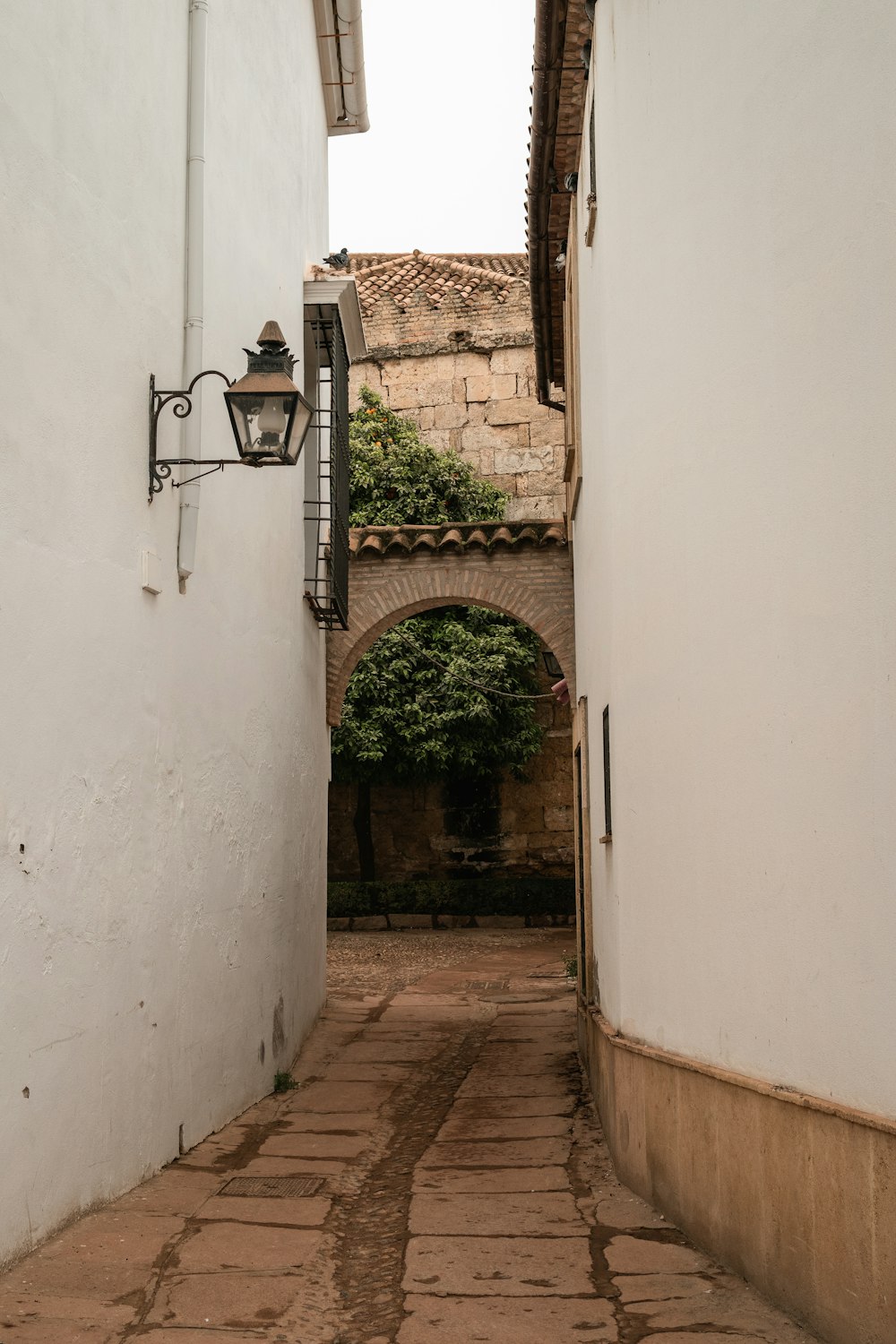 a narrow alley way with a lamp on the side