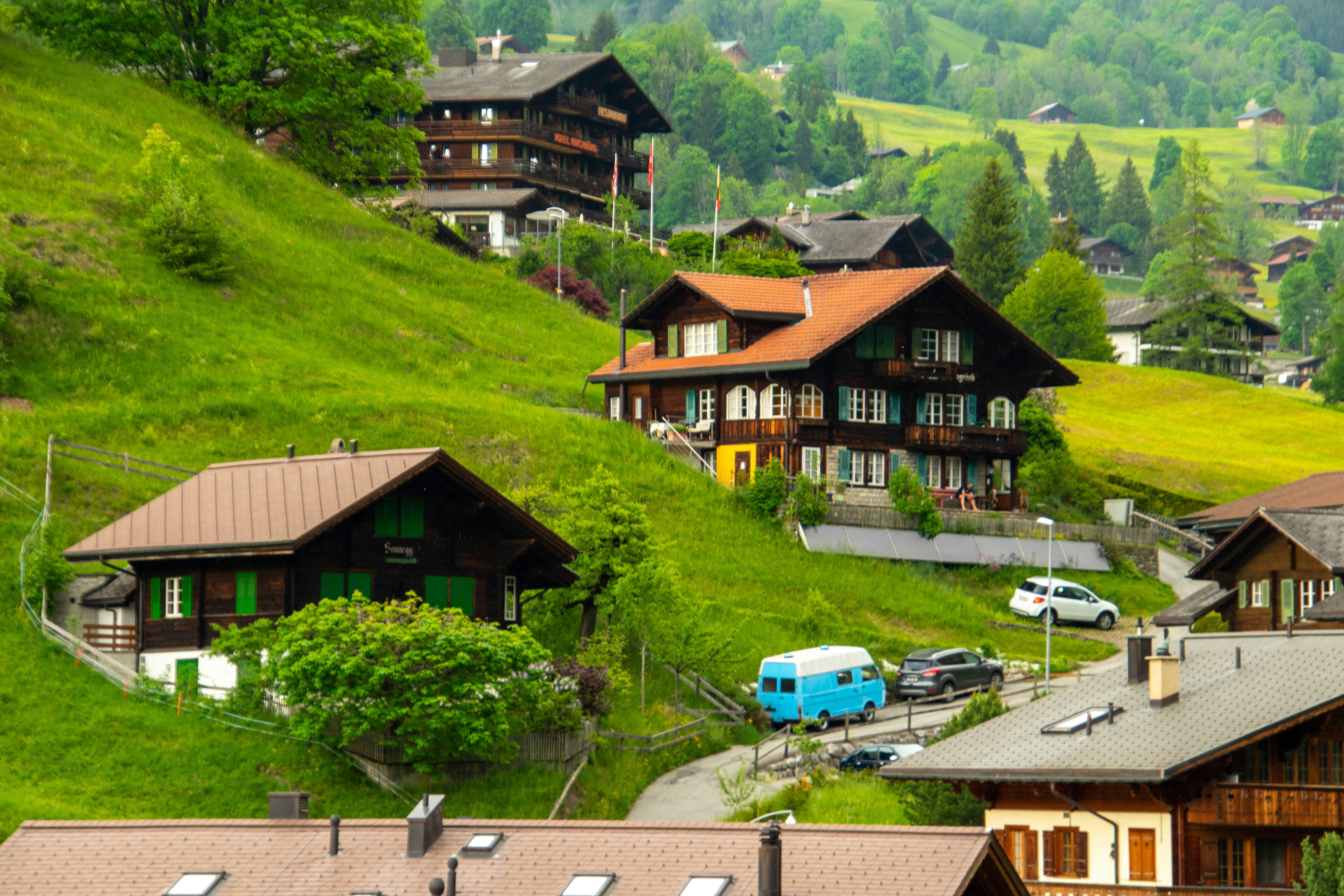 a group of houses on a hillside with cars parked in front of them, Country village 