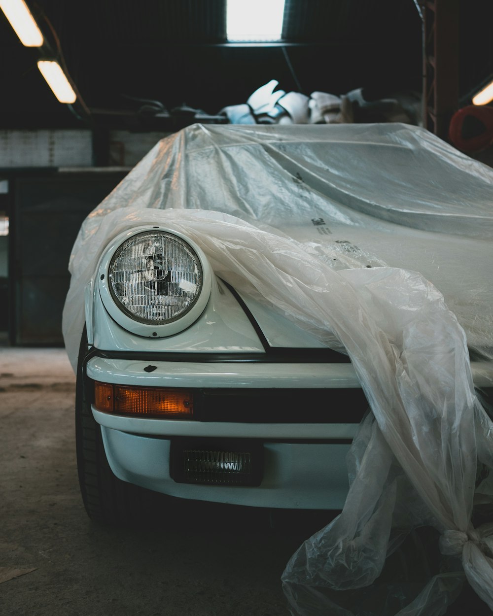a white car covered in plastic in a garage