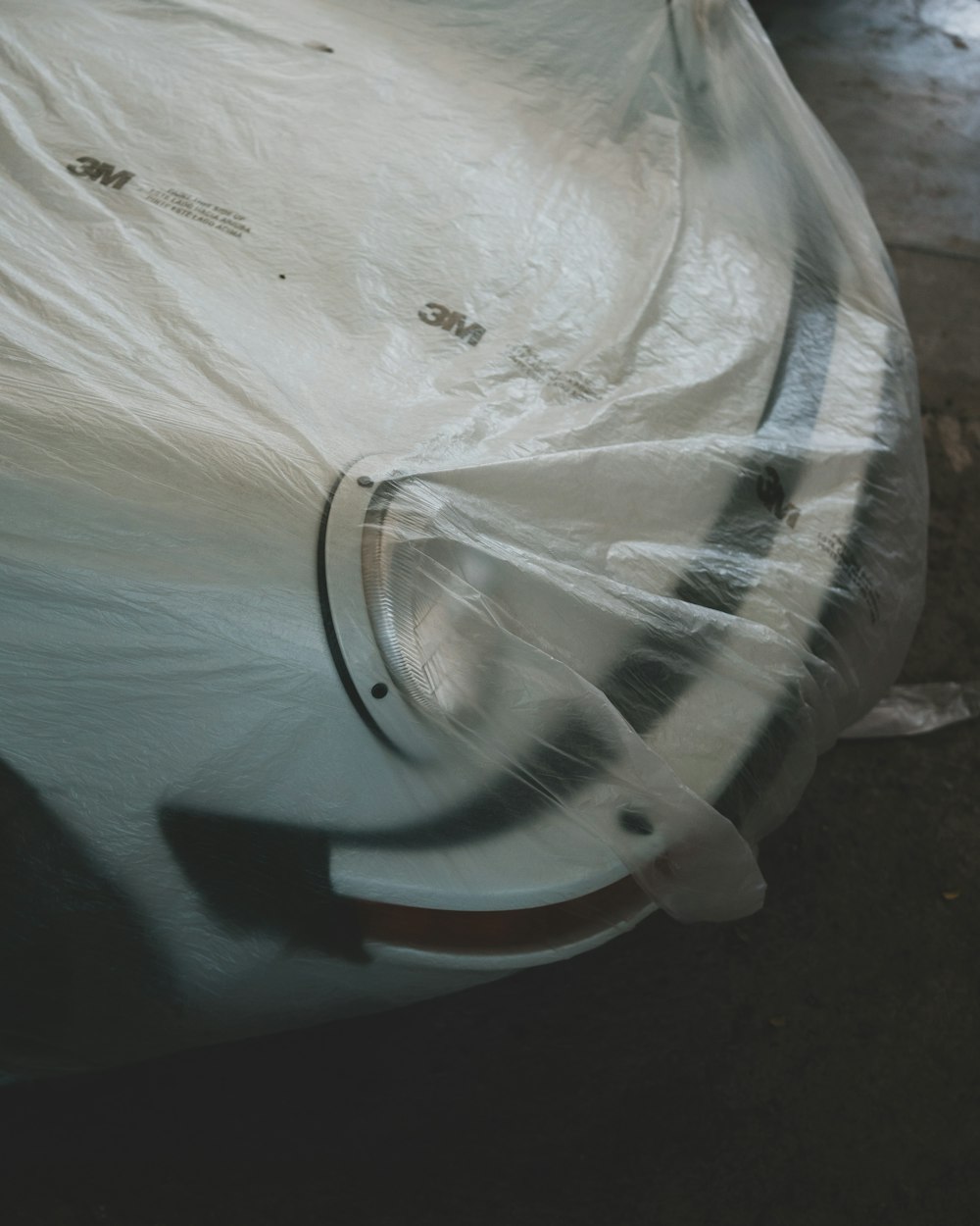 a car covered in plastic sitting on the ground