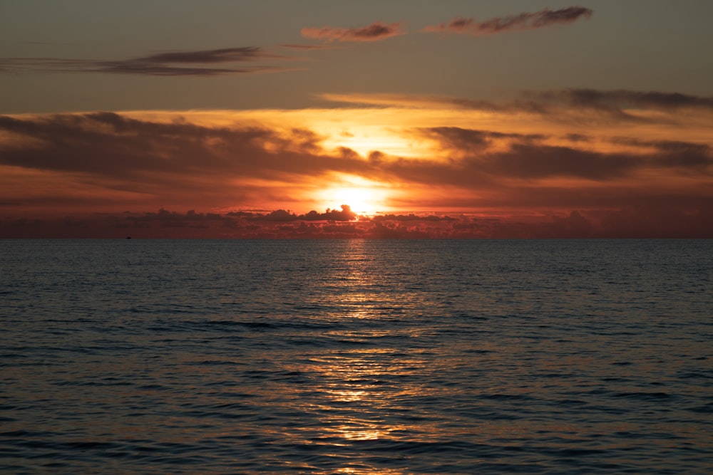 a large body of water with a sunset in the background