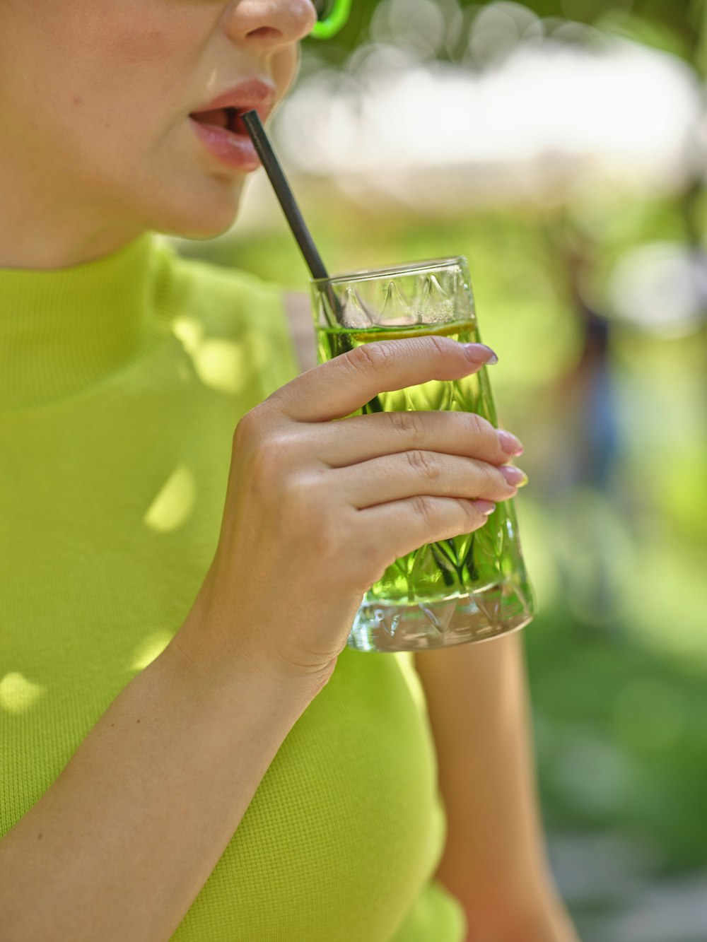 a woman in a green shirt drinking a green drink