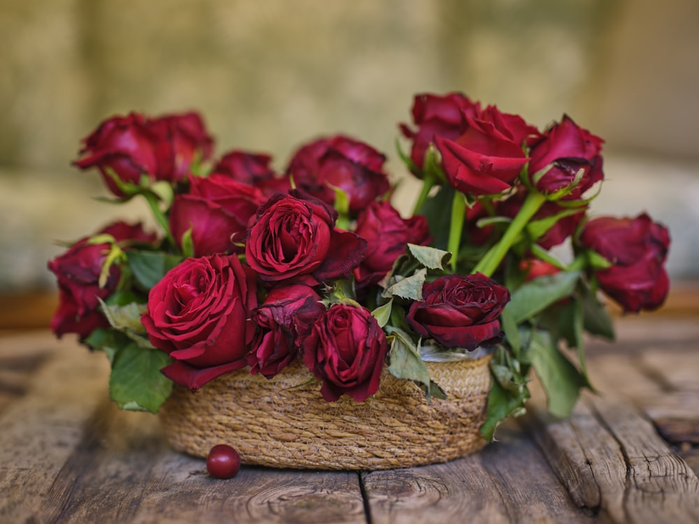a basket filled with red roses on top of a wooden table