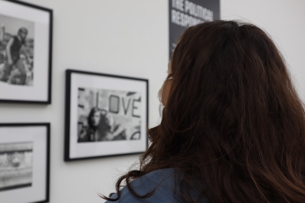 a woman standing in front of a wall with pictures on it