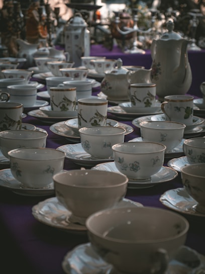 A display of European bone china plates and cups with delicate floral patterns arranged on a linen cloth.