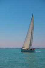 A vibrant sailboat gliding on the turquoise waters of Didim under a clear blue sky.