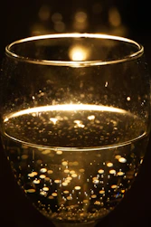 Close-up shot of crisp white wine glistening in the glass, reflecting the ambient light.