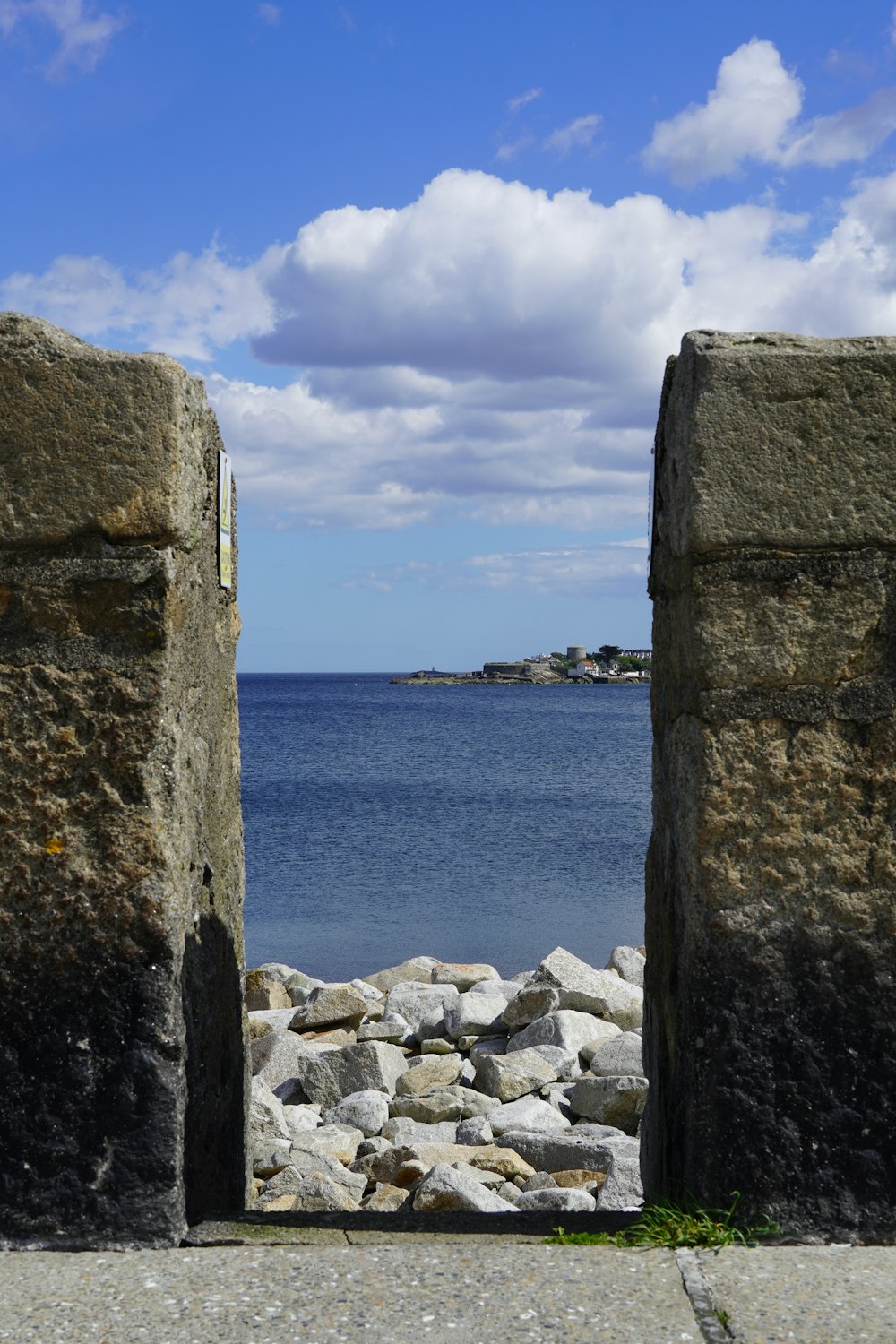 a view of a body of water through two stone doors