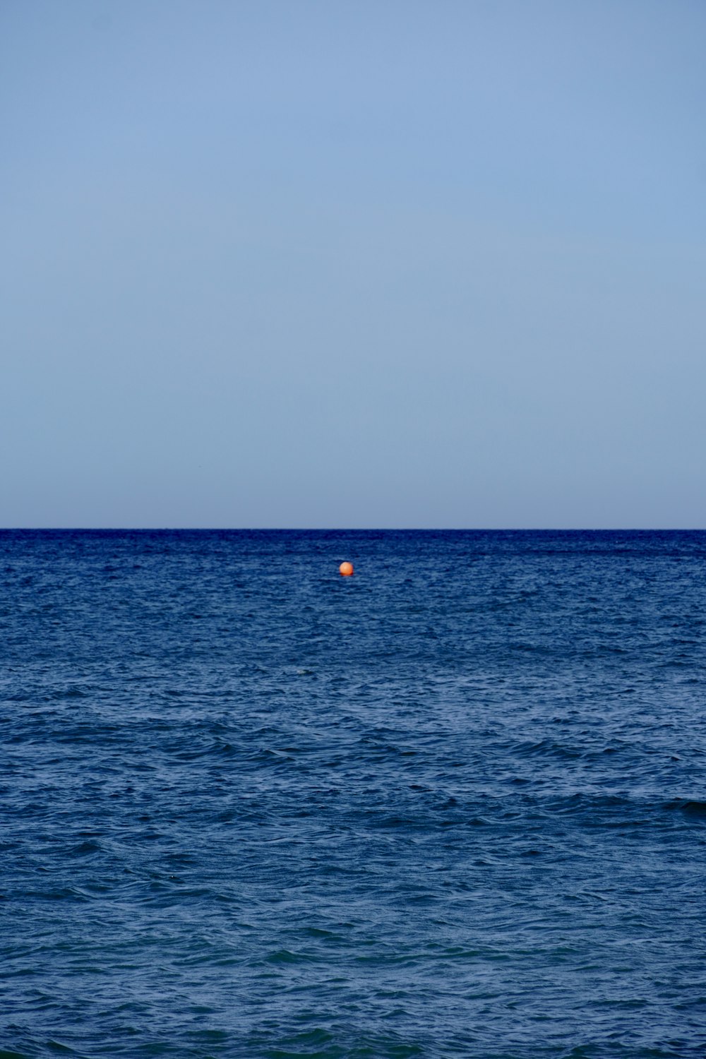 an orange buoy floating in the middle of the ocean
