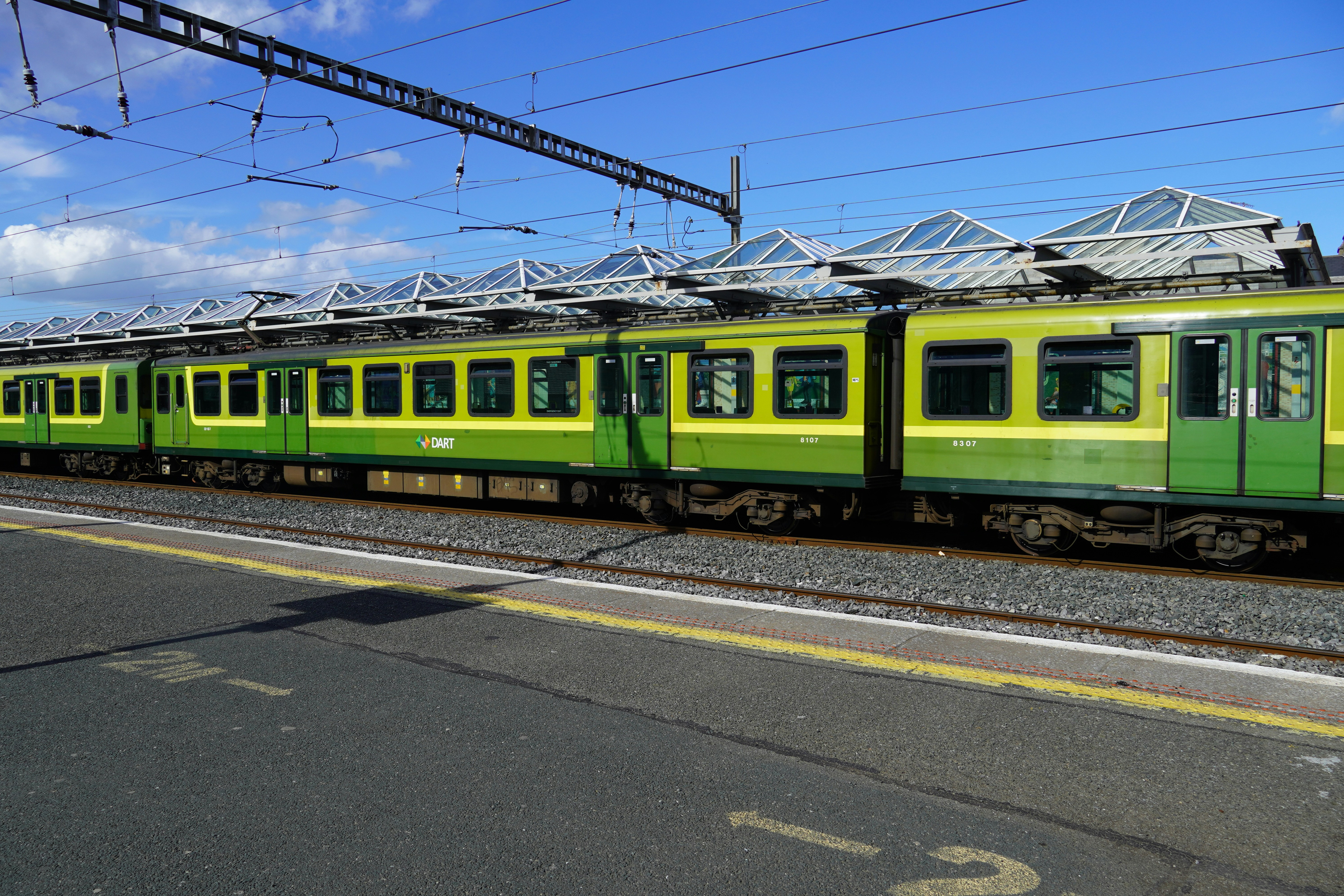 a green and yellow train traveling down train tracks