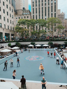 A vibrant group of roller skaters of all ages practicing on a sunny outdoor rink with a coach demonstrating techniques.