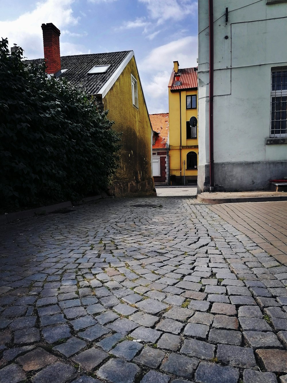 a cobblestone street with a yellow building in the background