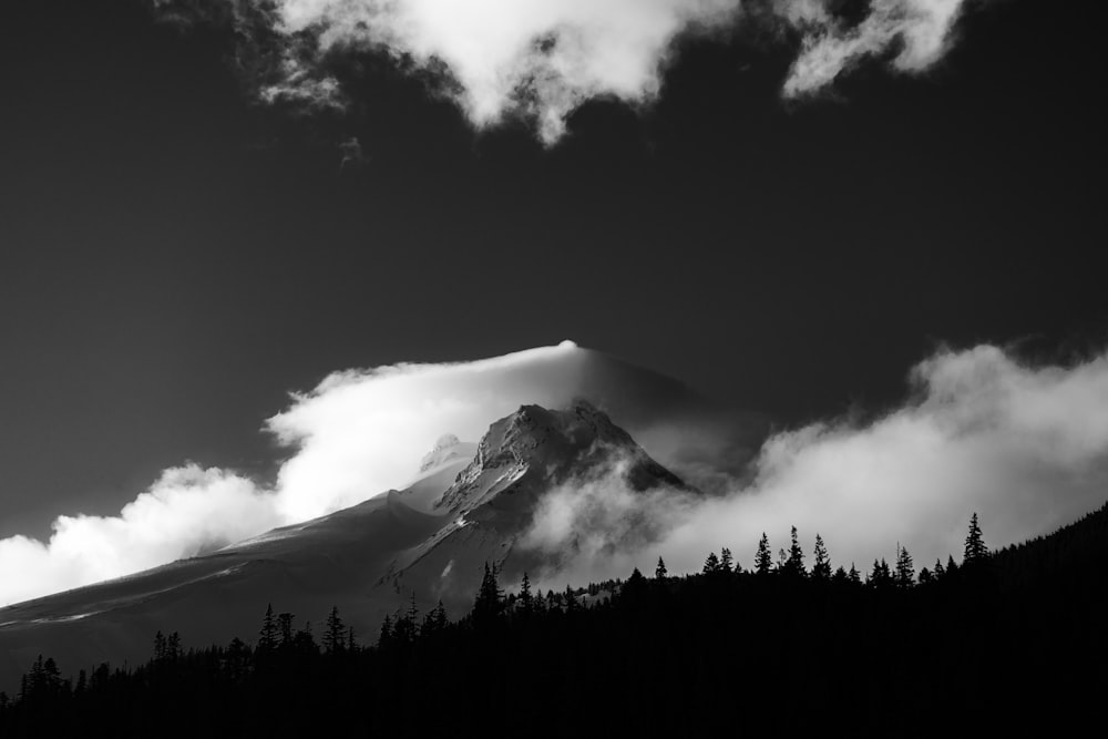 a black and white photo of a mountain covered in clouds