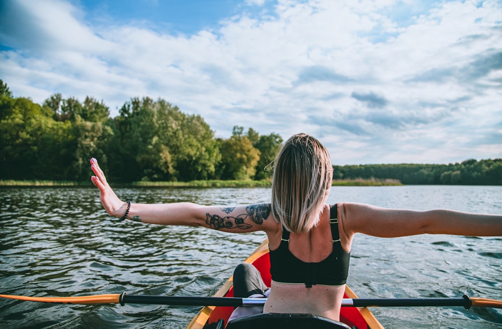 a woman with her arms outstretched in a canoe