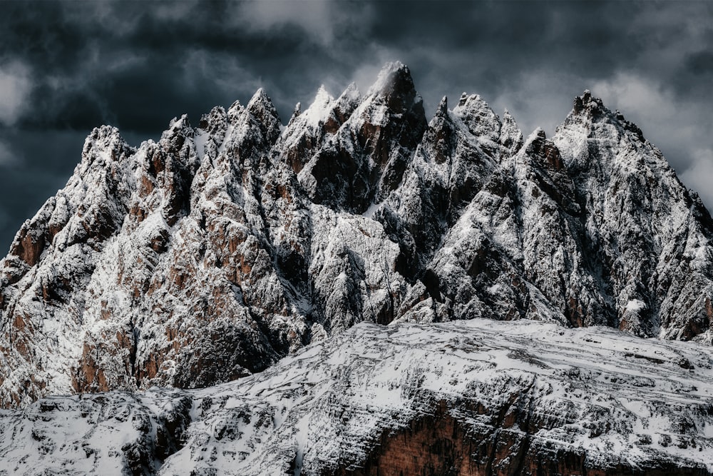 a mountain covered in snow under a cloudy sky