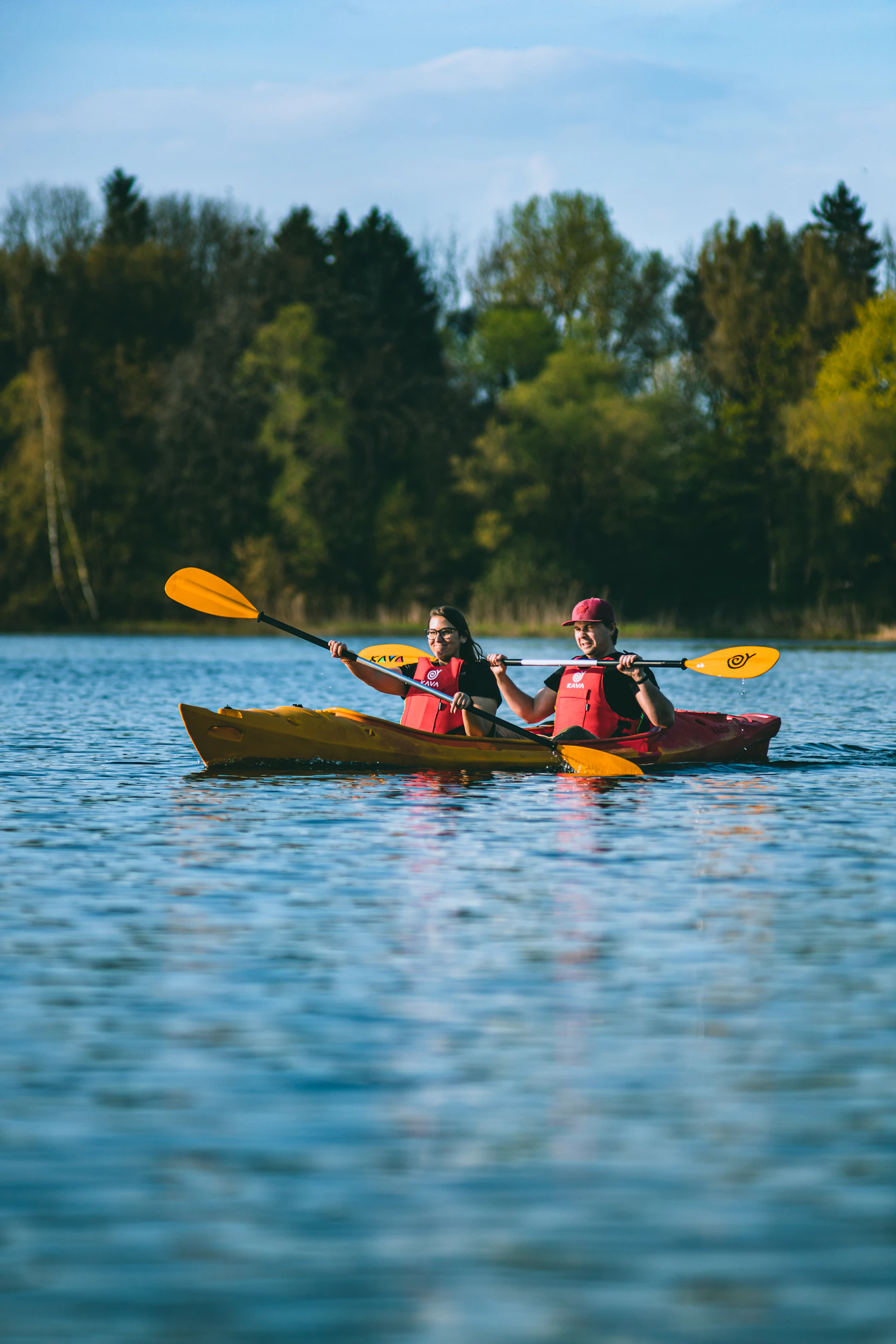 Kayakers wearing flotation aids while using paddling equipment on a lake