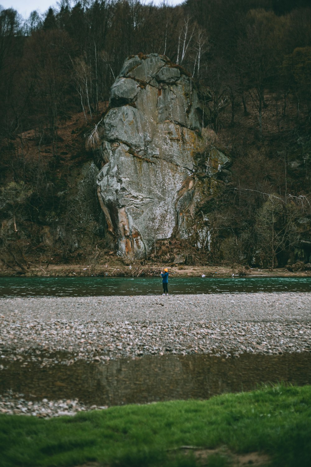 a man standing in a river next to a large rock