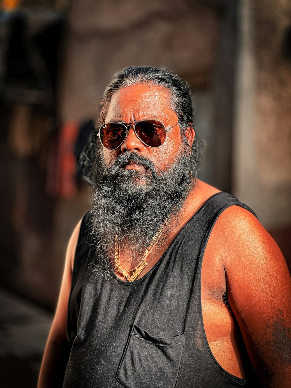 Ein Mann mit Bart mit Sonnenbrille und schwarzem Tanktop