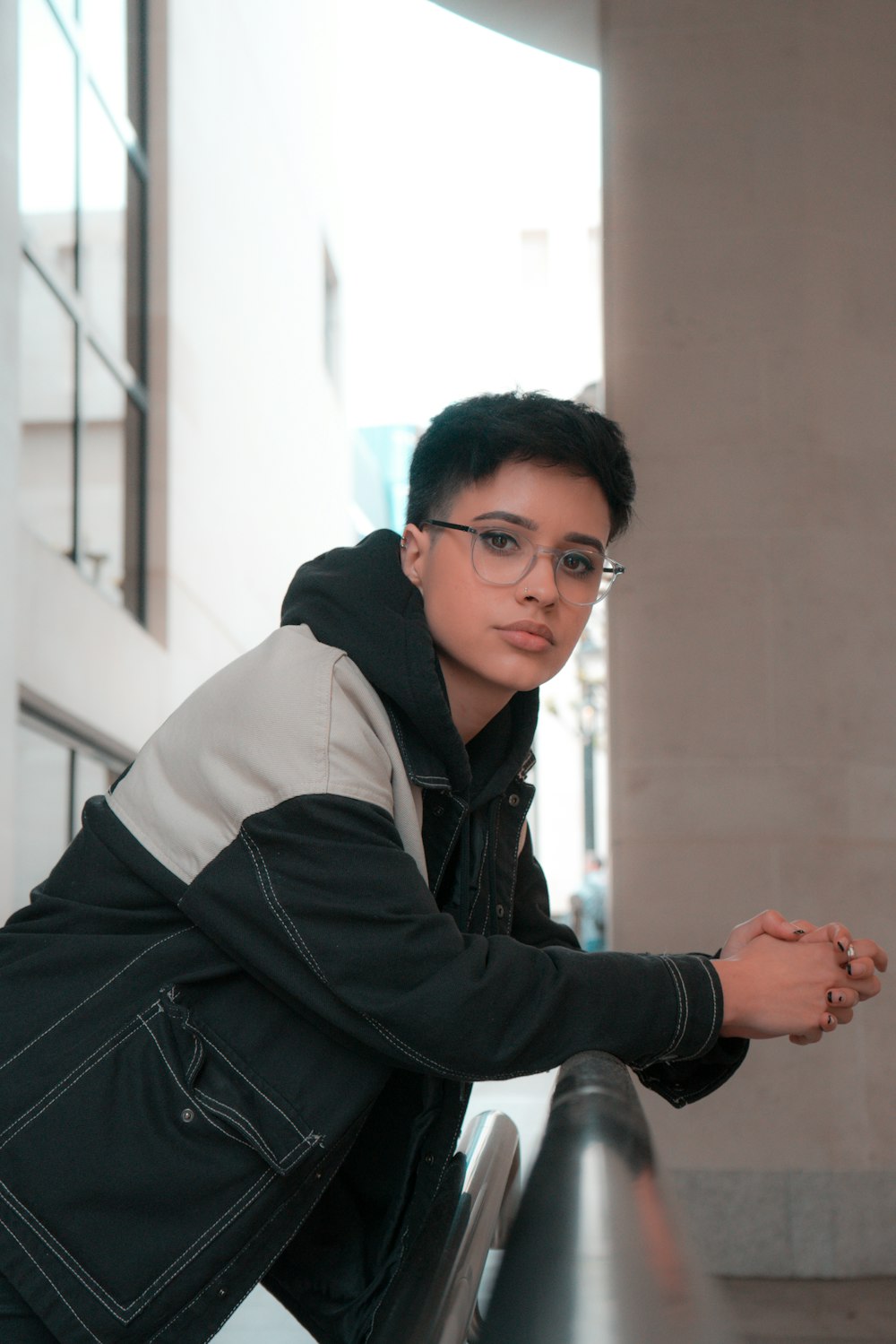 a man with glasses leaning on a railing