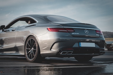 a silver mercedes benz coupe parked on a wet parking lot