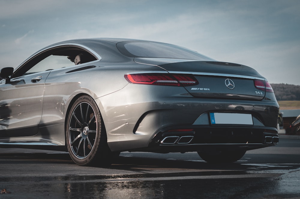 a silver mercedes benz coupe parked on a wet parking lot