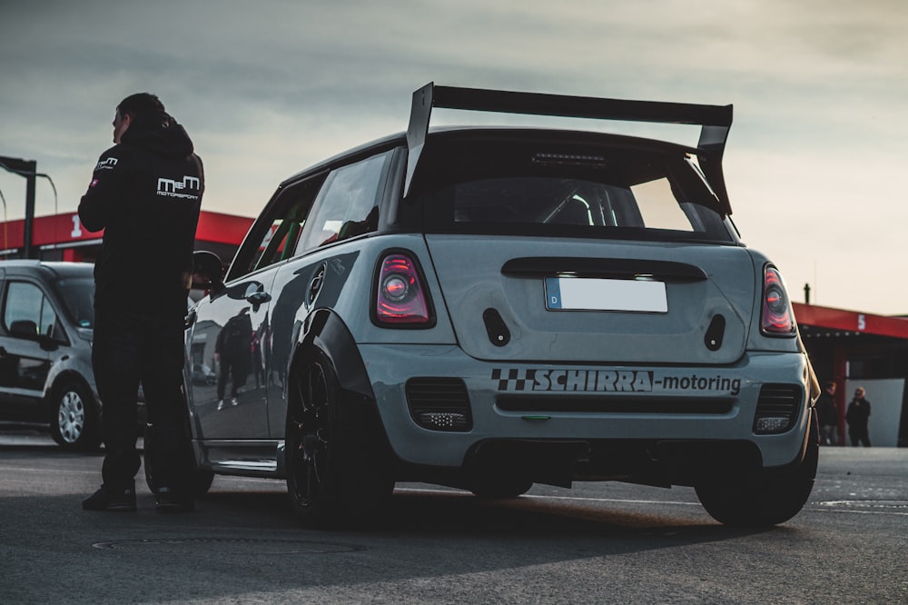 a man standing next to a mini cooper cooper cooper cooper cooper cooper cooper cooper cooper