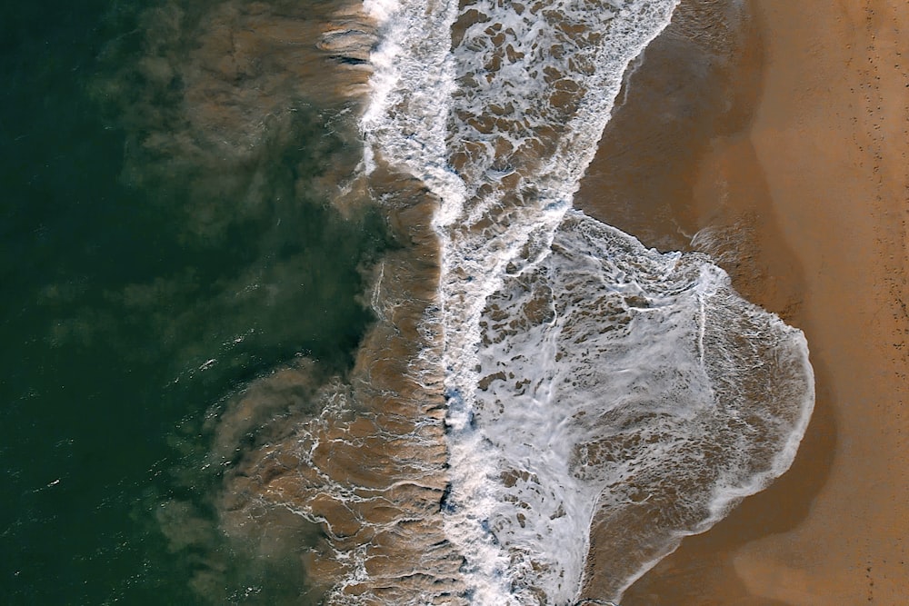 an aerial view of a beach with waves and sand