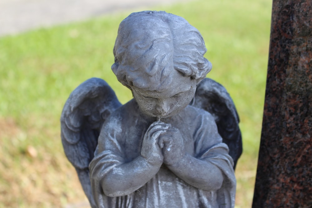 a statue of an angel is standing next to a tree