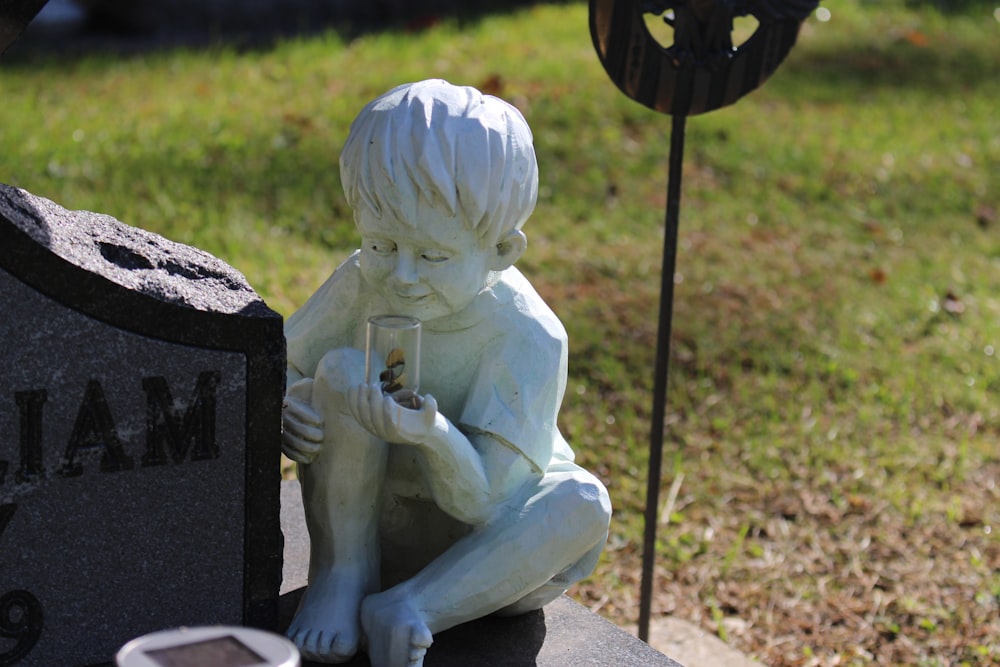 a statue of a boy sitting on top of a grave